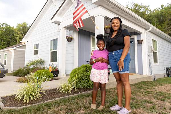 Adult and Child standing in front of white house